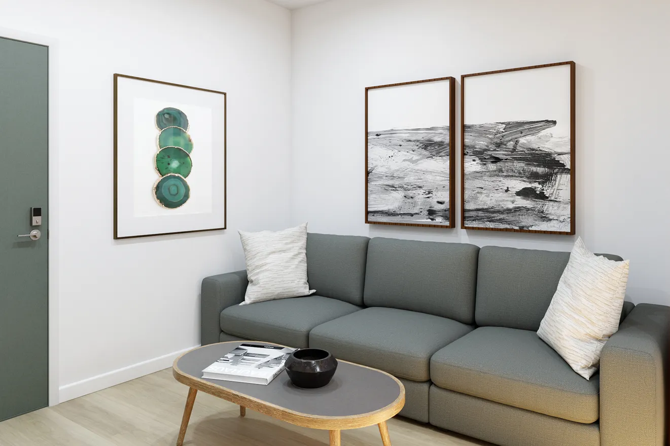 Modern living room with a gray sofa, white pillows, and a wooden coffee table. Two abstract black-and-white paintings and a green agate artwork adorn the walls.